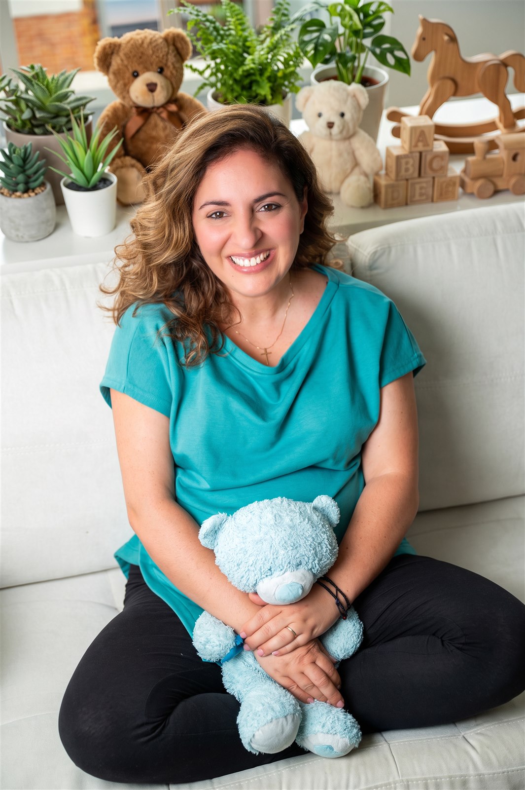 Maria Rakintzaki smiling with a teddy bear in her therapy space